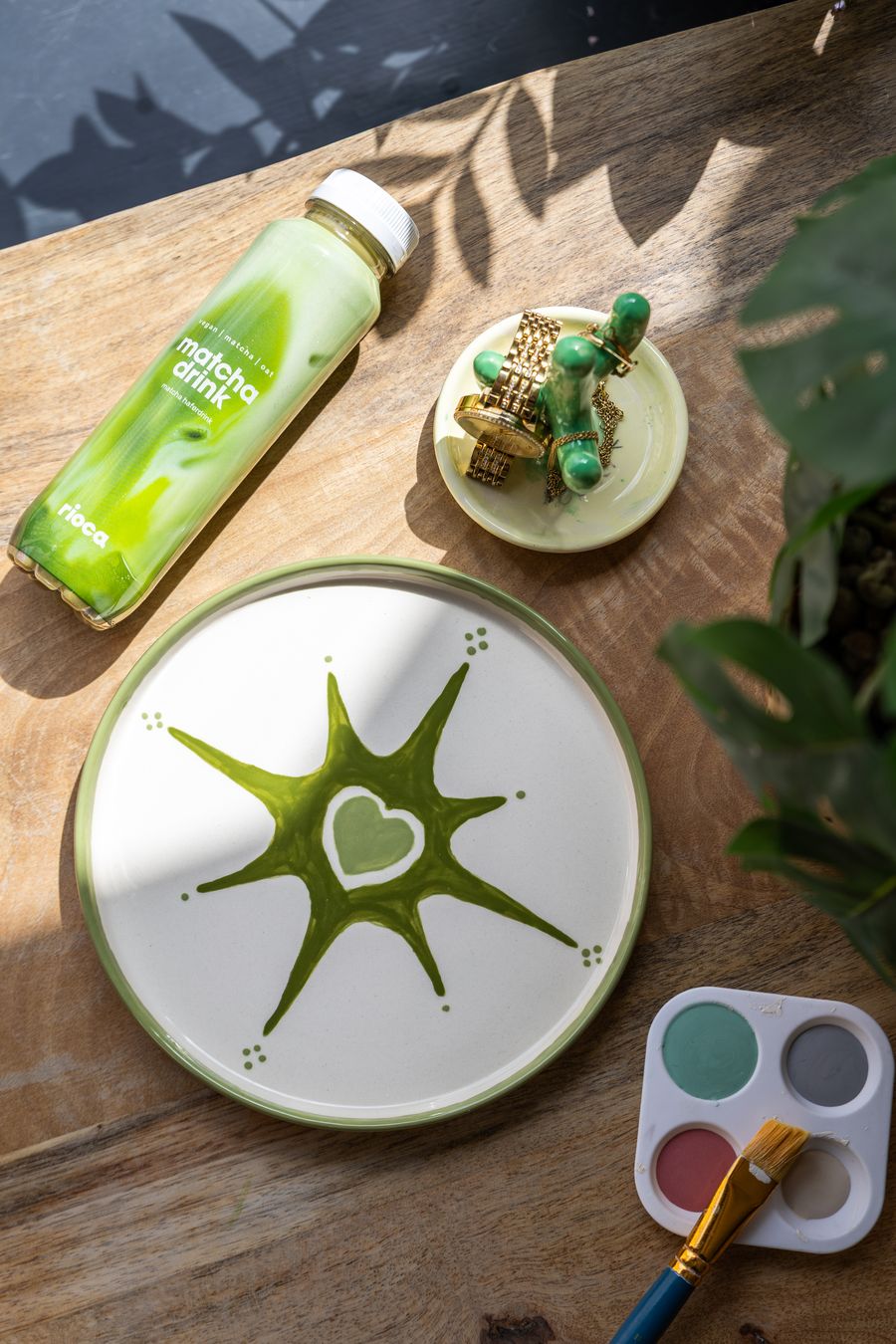 Bemalter Teller mit Matcha-Drink auf Holztisch — overhead